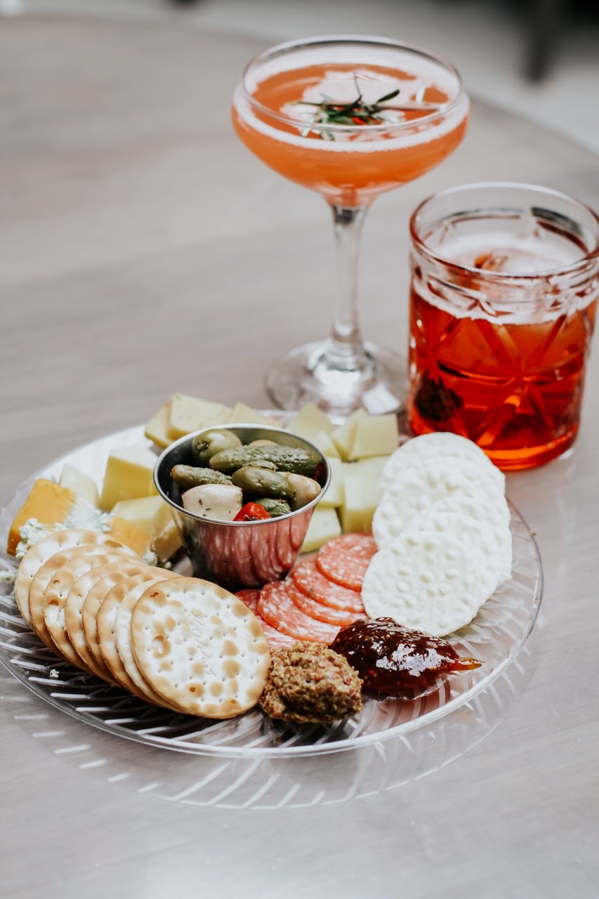 charcuterie board with stemmed and non-stemmed cocktails